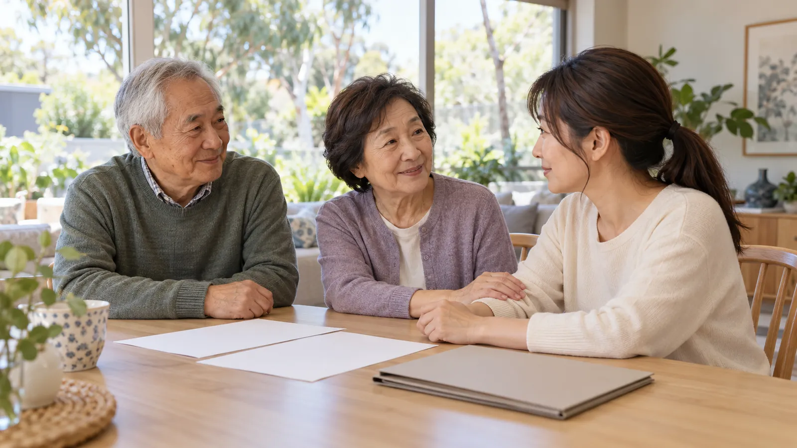 明るい自宅で書類を前に語り合い、娘の腕にそっと手を添える日本人の両親。
